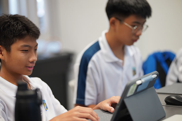 Two students focused on laptops in a classroom setting