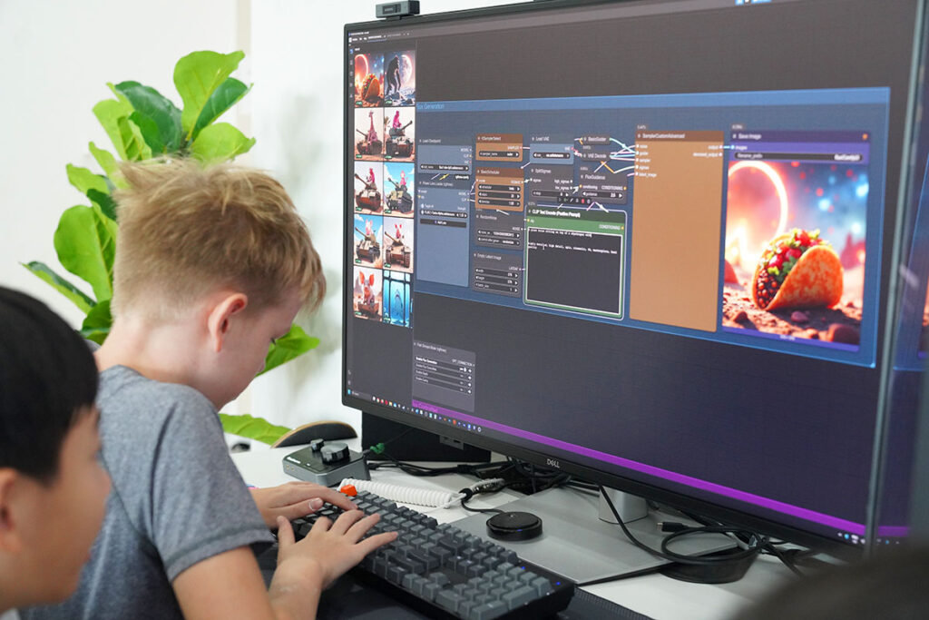 Two children use computer to create digital artwork on large monitor