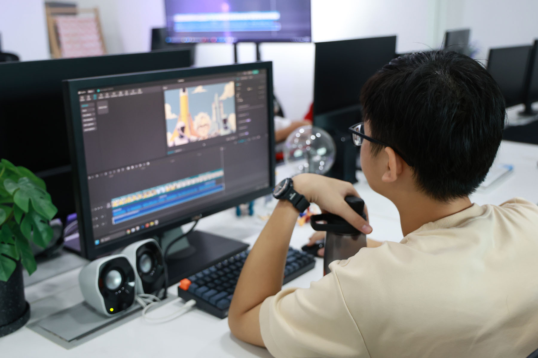 Young man edits video on computer in office setting