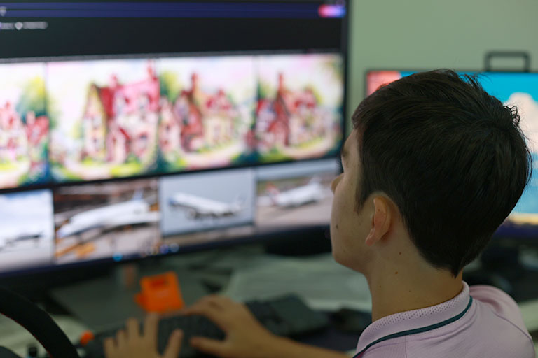 Young person monitors multiple video feeds on large computer screen