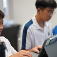 Two students focused on laptops in a classroom setting