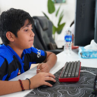Young boy focused on computer gaming setup with keyboard and mouse