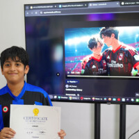 Young boy holds certificate, smiles in front of screen displaying anime video