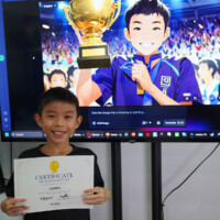 Young boy holds certificate, smiling in front of large screen displaying cartoon athlete