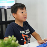 Young boy sits at desk, typing on keyboard, focused on computer screen
