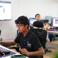 Young man focused on computer work in a bright, busy office environment