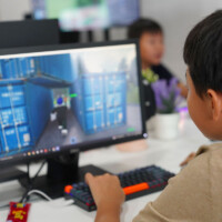 Young boy focused on gaming monitor displaying blue container game