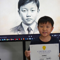 Young boy holds certificate, stands before screen displaying his portrait