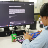 Girl typing on keyboard, computer screen displaying text