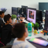 Children work at computers in a tech-filled office space