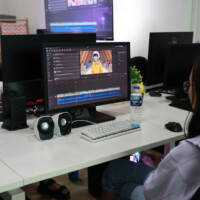 Person working on video editing software at a desk with multiple monitors