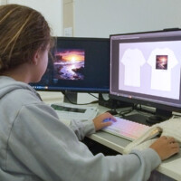 Person designs t-shirt graphics on computer with dual monitors