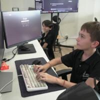 Young boy focused on computer, typing with keyboard and mouse