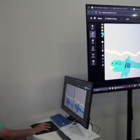 Child draws shark illustrations on digital screen at workstation