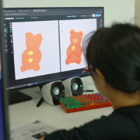 Person designs two orange teddy bear illustrations on computer screen