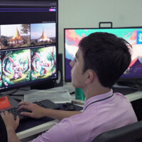 Man works at video editing station with multiple monitors and gaming controller