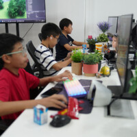 Three young boys focused on computer screens in a bright office
