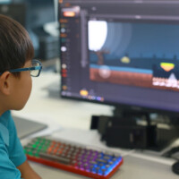 Young boy with glasses focuses on video editing software on computer screen