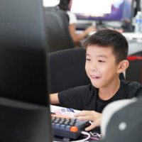 Young boy smiles while using computer keyboard in gaming setup