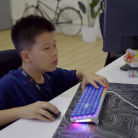 Young boy focused on computer gaming with glowing keyboard