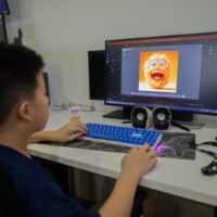 Young boy uses computer to edit colorful digital artwork on screen