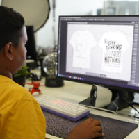 Young boy designs t-shirt graphics on computer screen