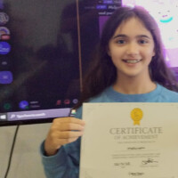 Young girl smiles while holding a certificate of achievement