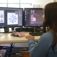 Person works at desk with two monitors displaying design software