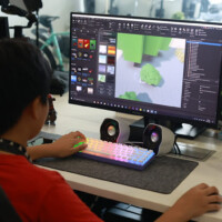 Child uses computer to design 3D game levels with colorful keyboard