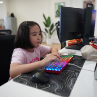 Young girl focused on typing with colorful keyboard at desk