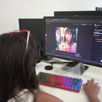 Person edits anime-style image on computer with colorful keyboard