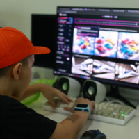 Young person edits video on computer with colorful thumbnails displayed