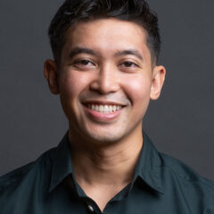 Smiling man in dark shirt against gray background