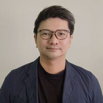 Man with glasses and dark jacket smiles at camera